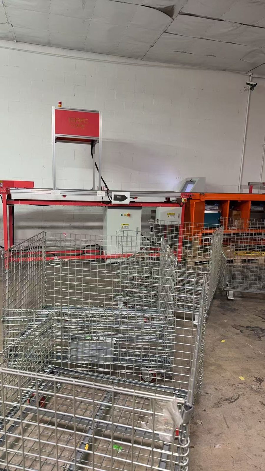The wall-side sortation line with roll cages staged at the discharge end